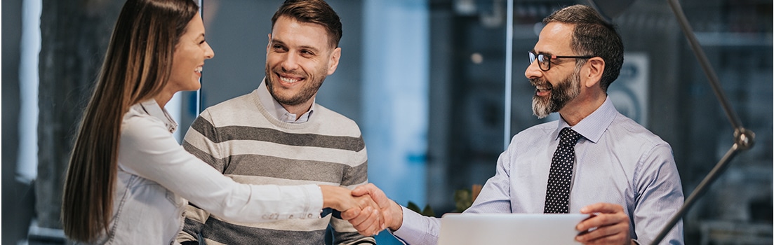 Three people in an office, with two of them shaking hands
