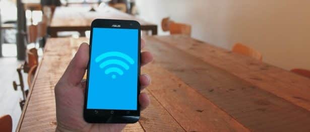 A person's hand holding a cell phone showing the Wi-Fi symbol
